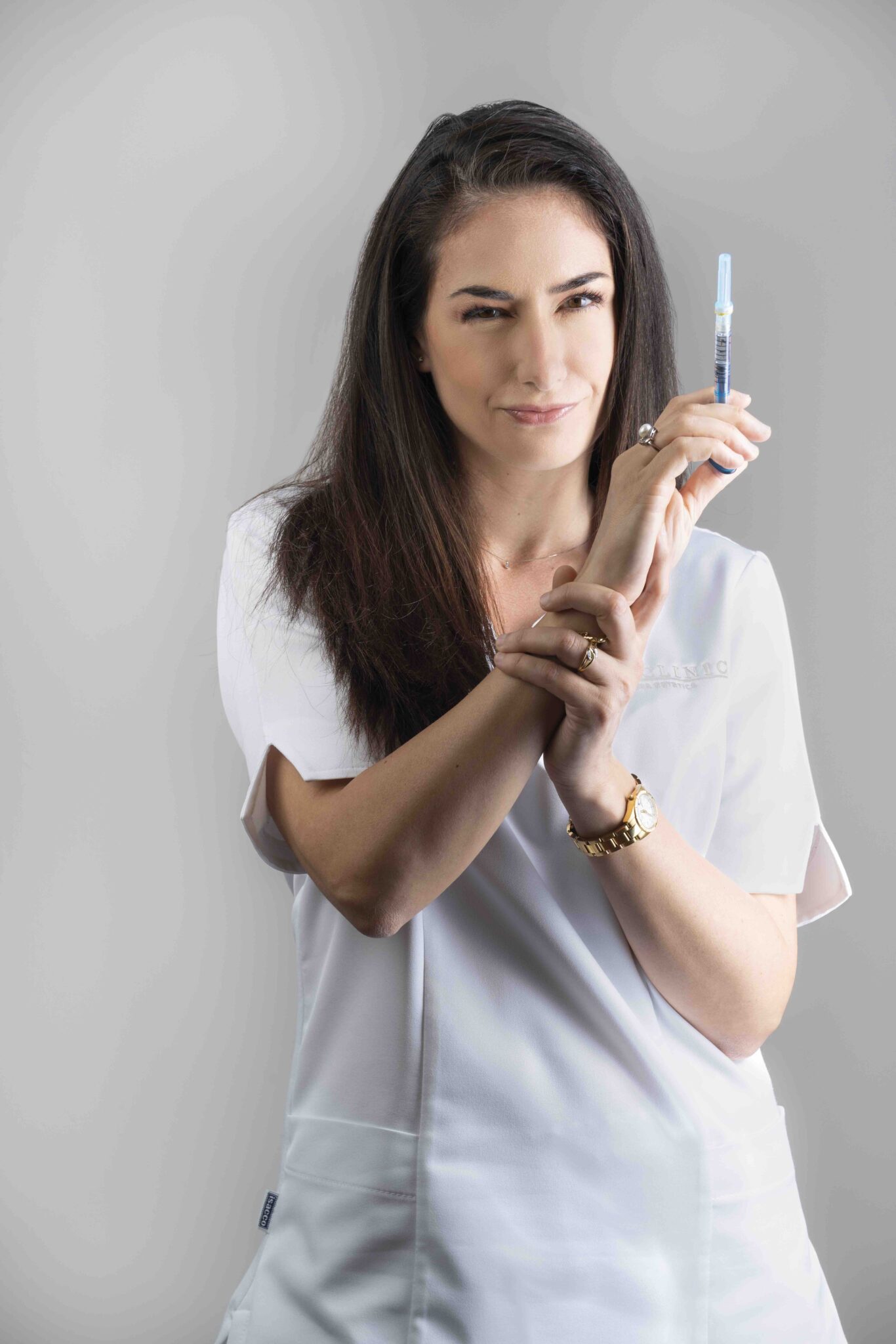 Ritratto della Dott.ssa Carla Cucca con una siringa per trattamenti iniettivi, nello studio Alta Clinic di Bergamo