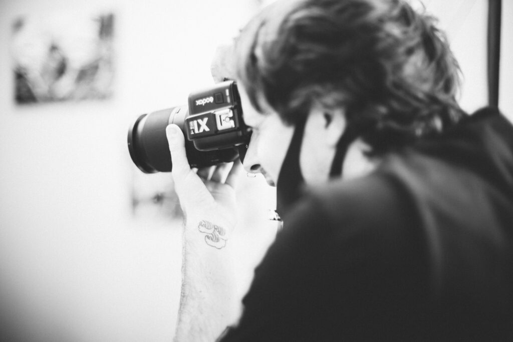 Fotografo con fotocamera in mano durante gli scatti in bianco e nero del backstage 2020 di Alta Clinic a Bergamo