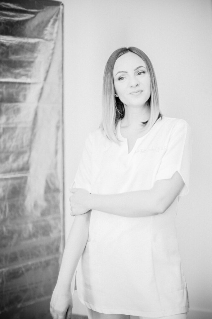 Donna bionda in divisa bianca in posa davanti al fondale durante il servizio fotografico Alta Clinic del 2020