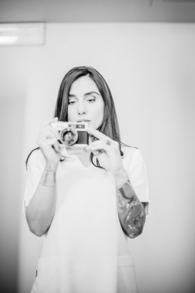 Donna in divisa bianca scatta una foto con una fotocamera compatta durante il backstage 2020 di Alta Clinic Bergamo