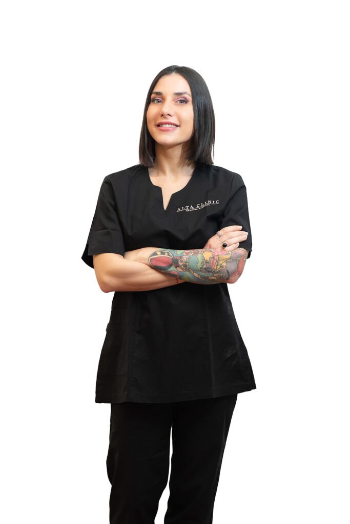 Giorgia in divisa nera Alta Clinic con le braccia tatuate incrociate, ritratto a figura intera per la sua pagina dello staff